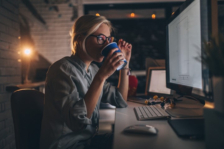 Una mujer bebiendo café mientras trabaja en el ordenador