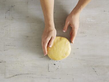 hands holding a circle mound of shortcrust pastry